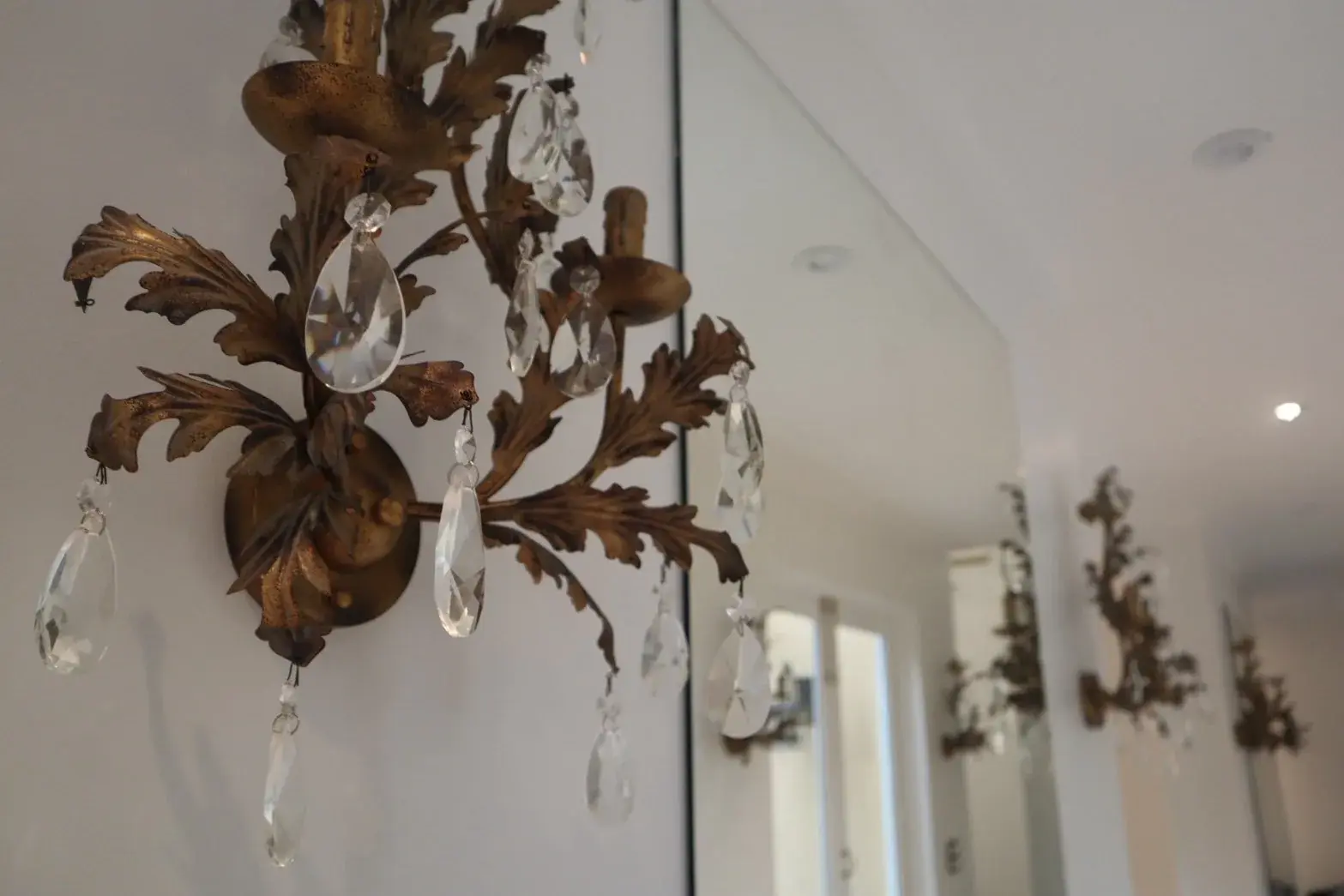 Close-up of an antique brass and crystal sconce on a freshly painted white wall
