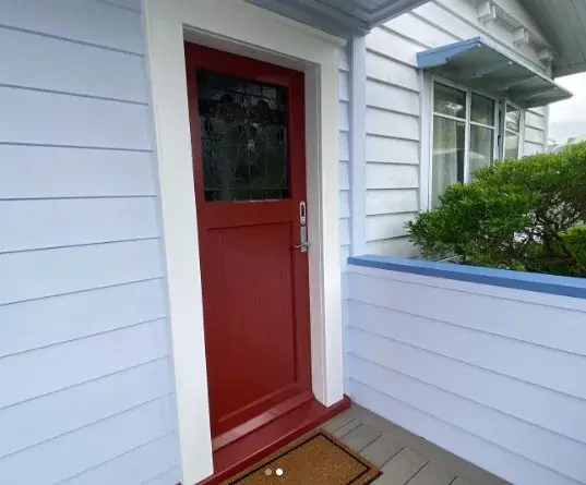Bold red front door on a freshly painted white weatherboard cottage