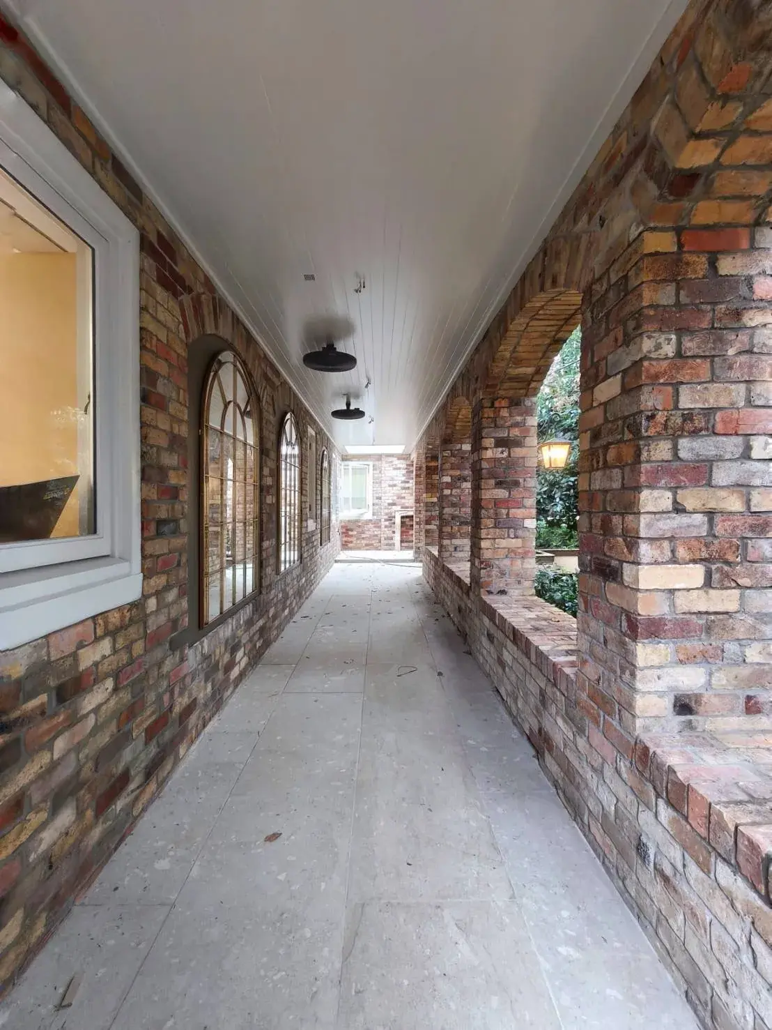 Heritage brick walkway with arched openings and freshly painted white ceiling