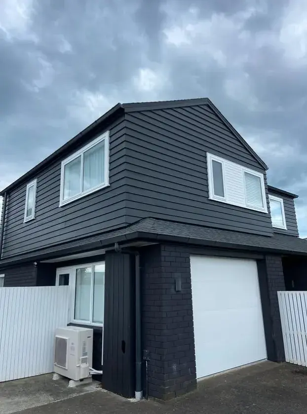 Two-storey dark grey weatherboard home with white trim painted by Tommy Paint Redo