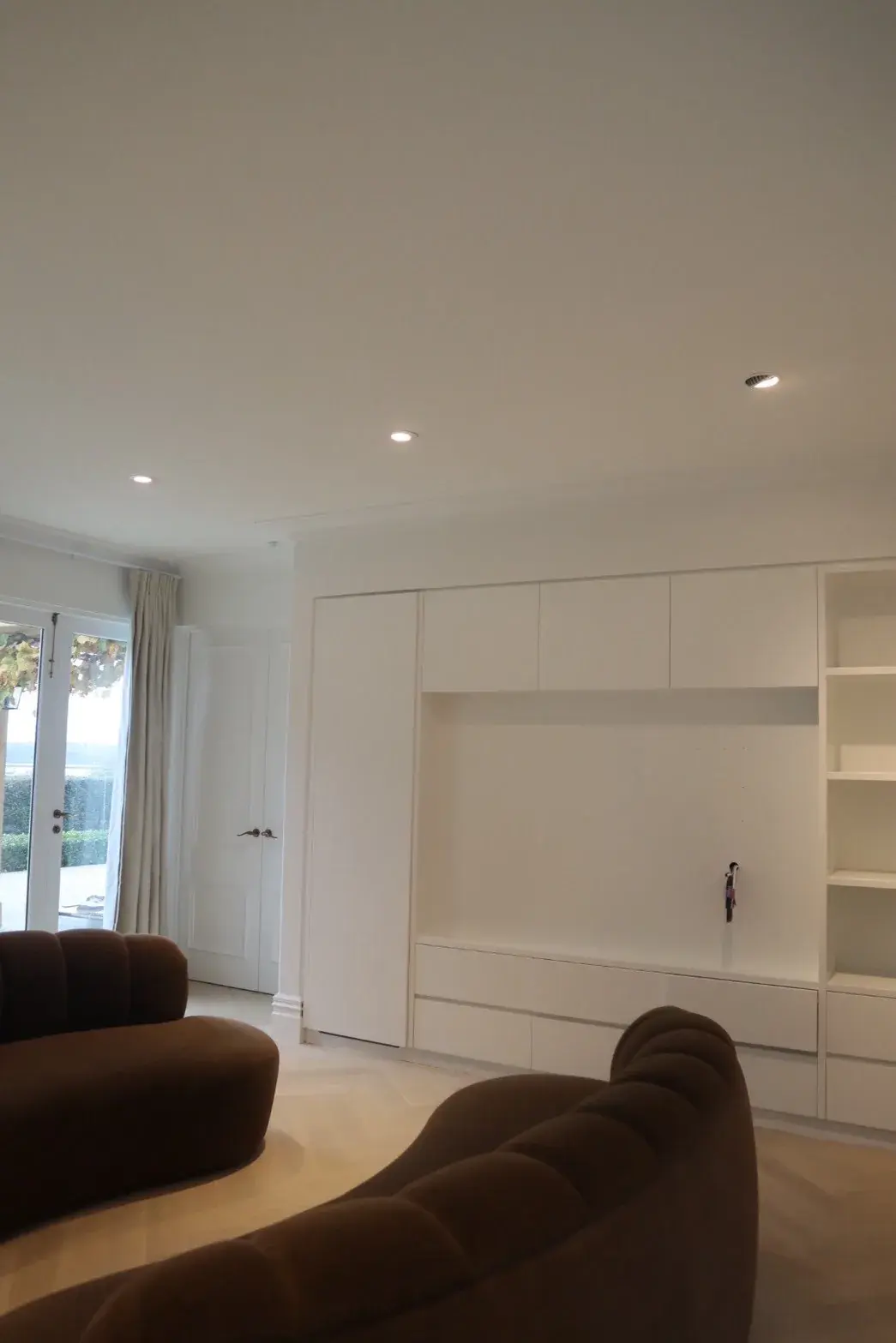 Modern Auckland living room with crisp white painted built-in shelving and cabinetry