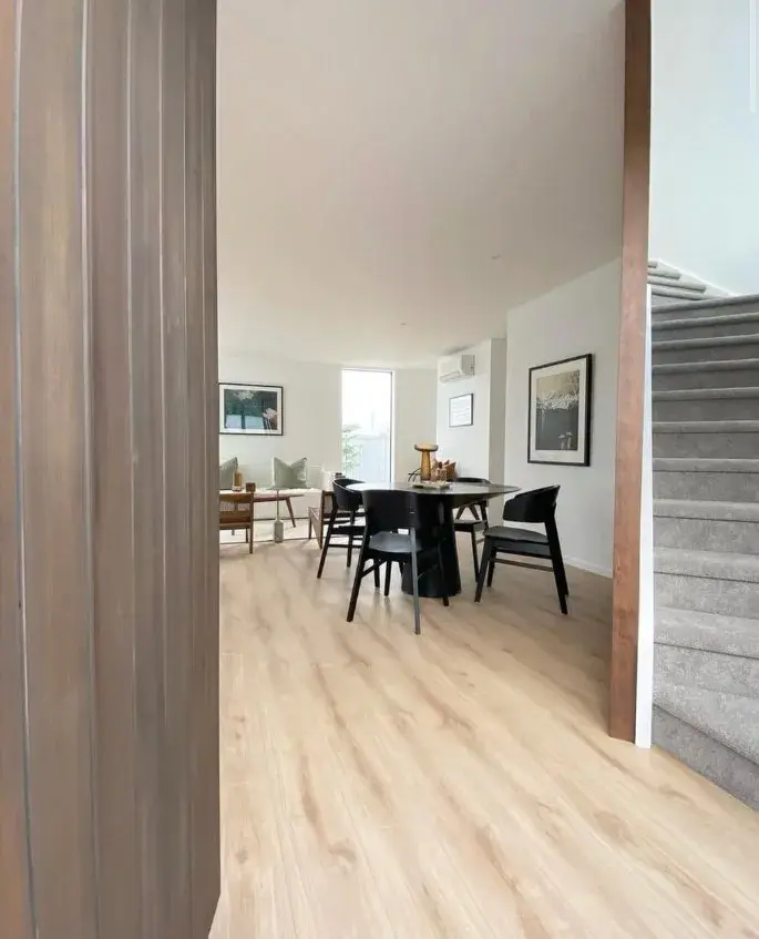 Dining and hallway space with neutral painted walls leading to lounge