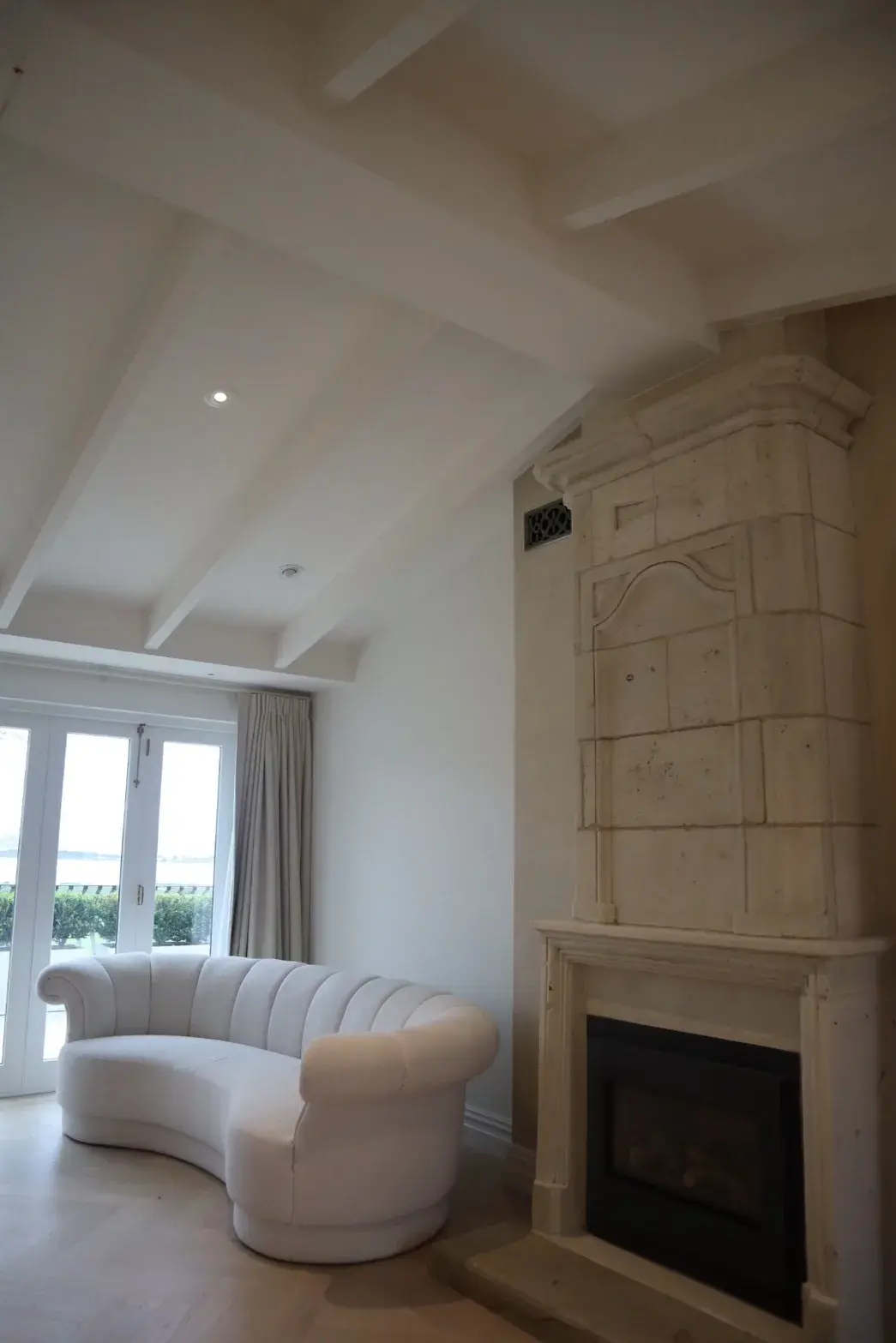 Auckland heritage living room with grand stone fireplace and white painted beam ceiling