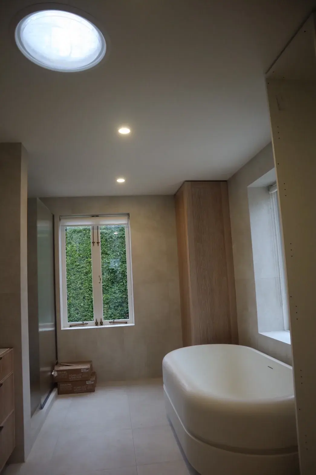 Modern Auckland bathroom with soaking tub, oak panelling and painted ceiling beneath a skylight