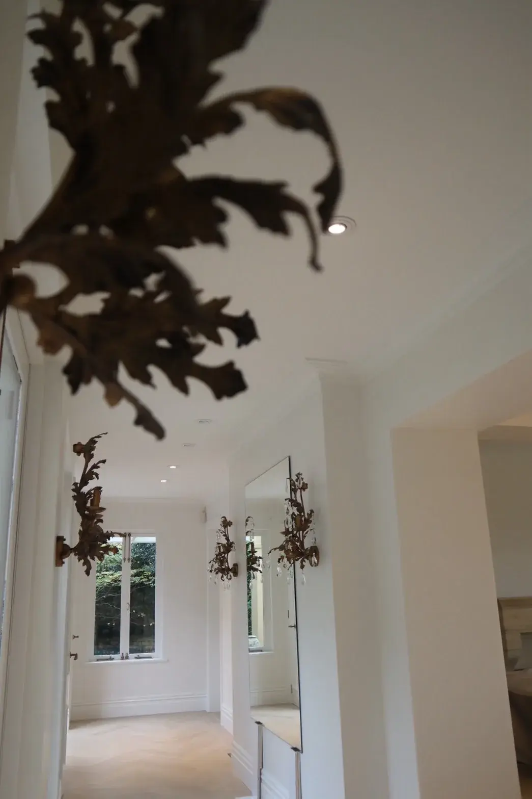 White painted hallway with multiple antique sconces and panelled wainscoting