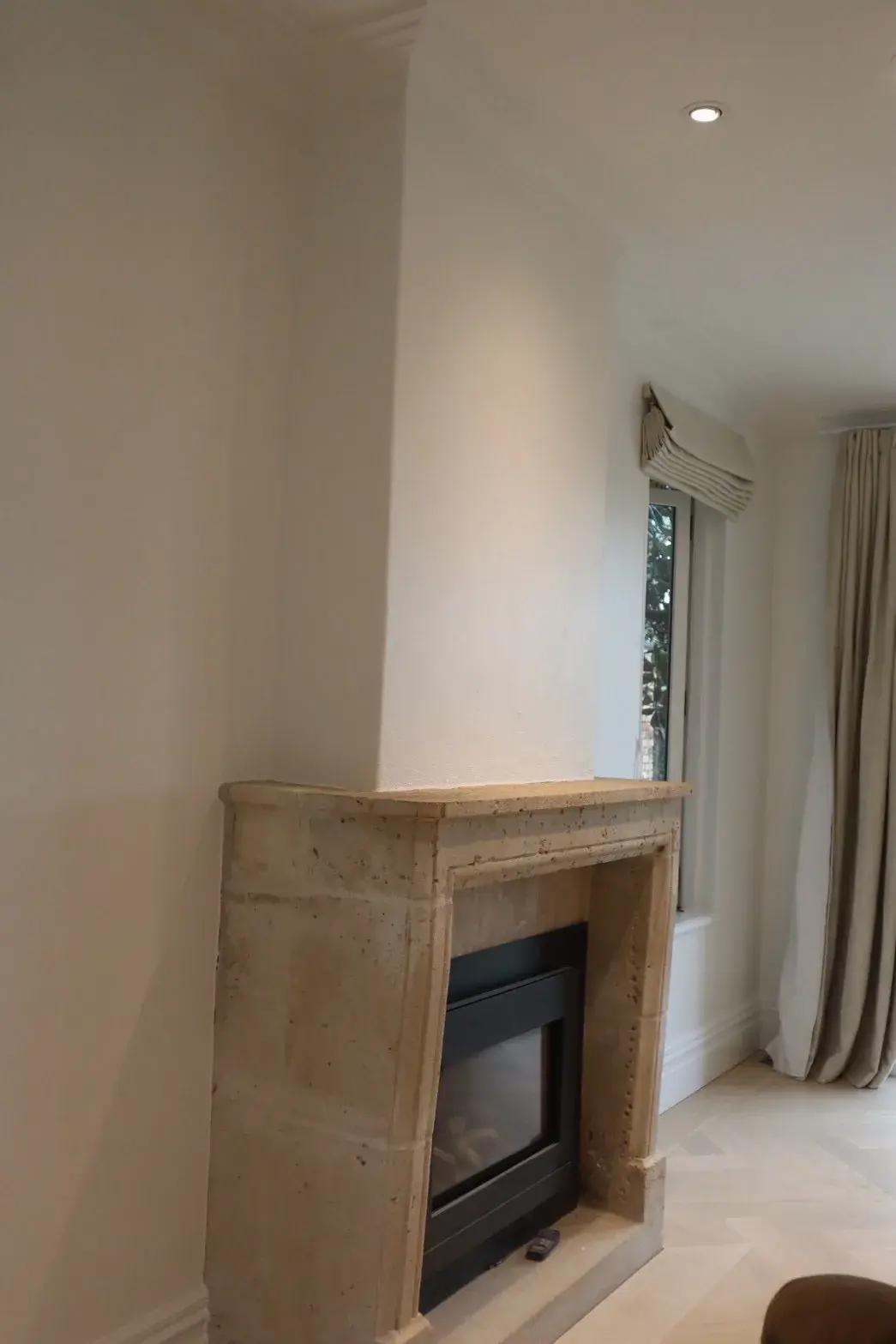 Travertine stone fireplace against freshly painted white walls in an Auckland renovation