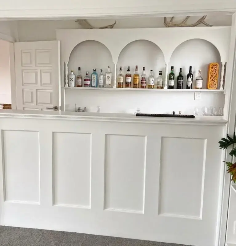 White wainscoting feature bar wall with arched display shelves