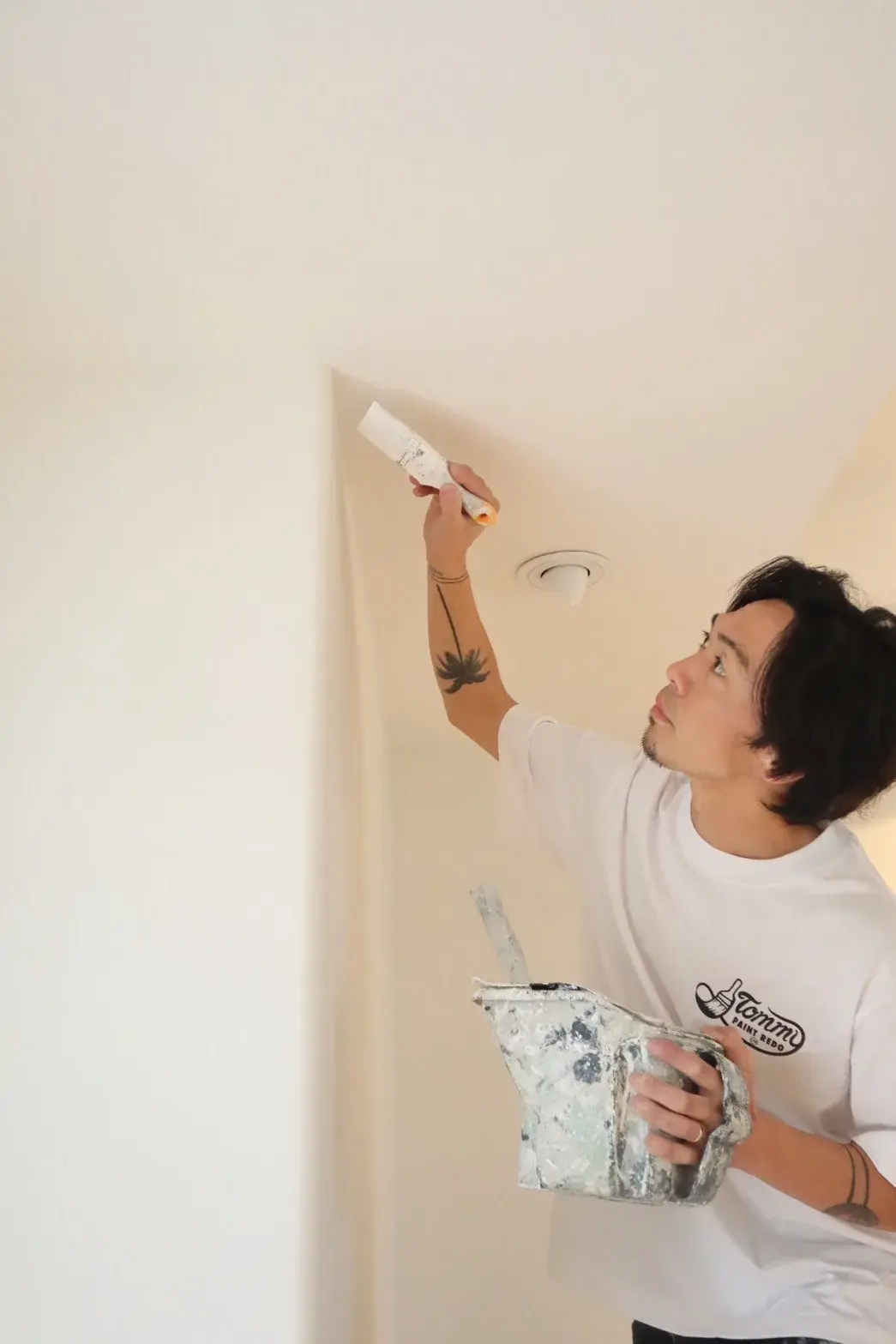 Tommy from Tommy Paint Redo in a branded t-shirt painting a ceiling on an Auckland job