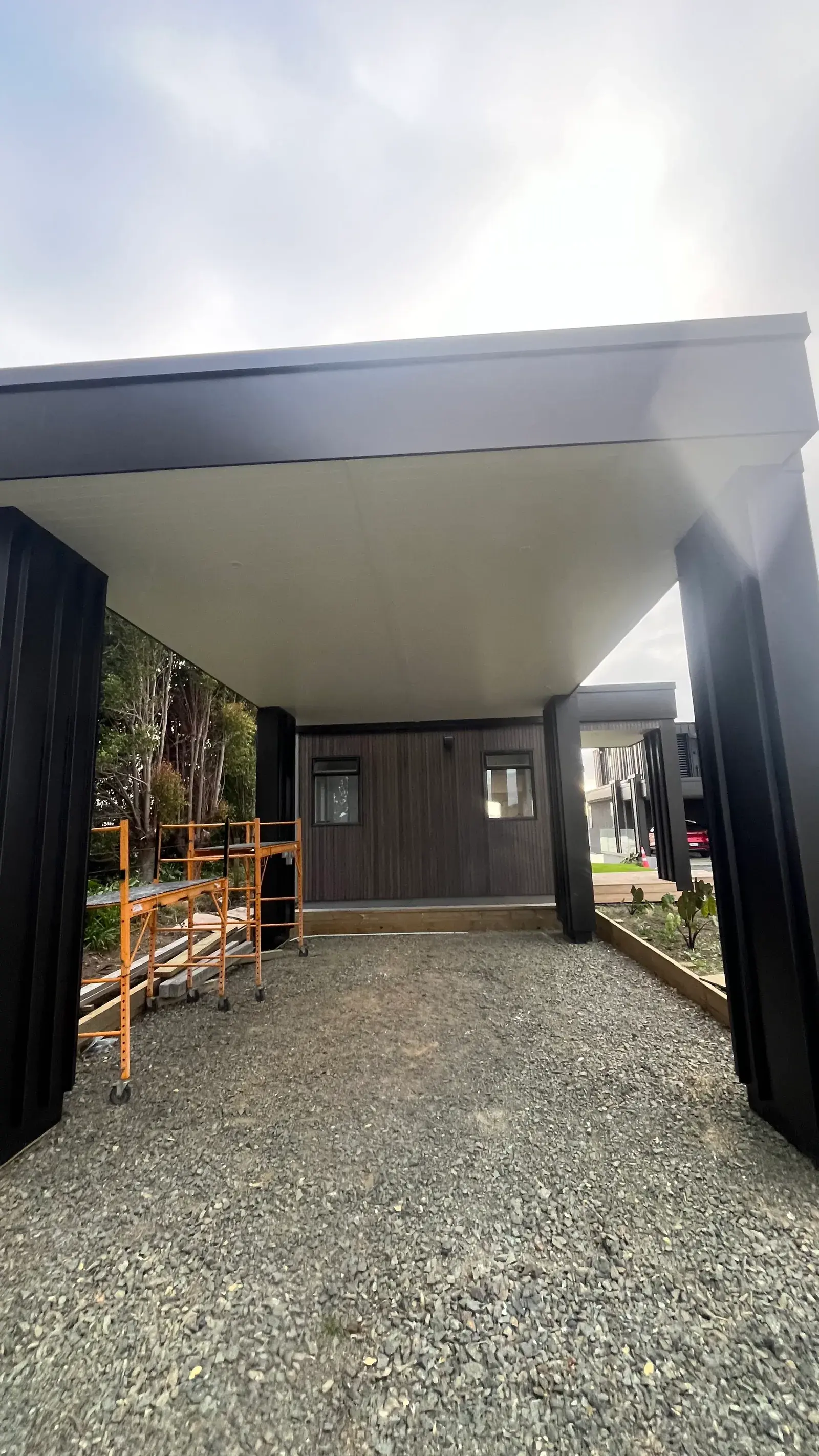 Modern black new-build home and carport being painted in Auckland