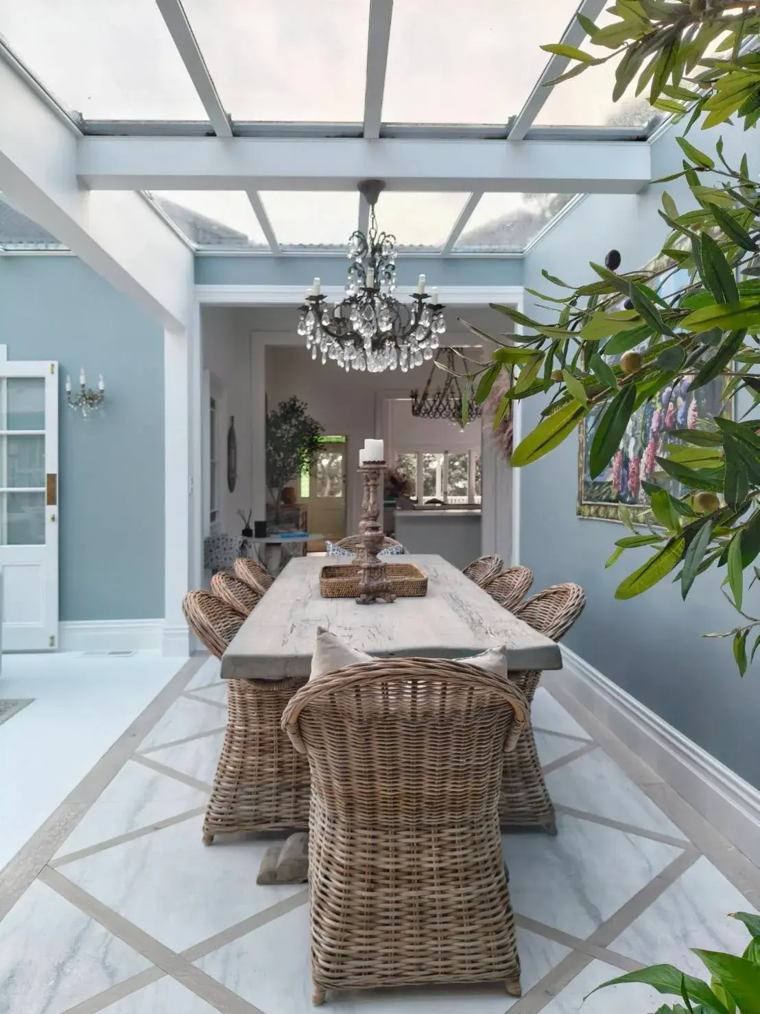 Conservatory dining room with glass roof and soft blue-grey painted walls in Auckland